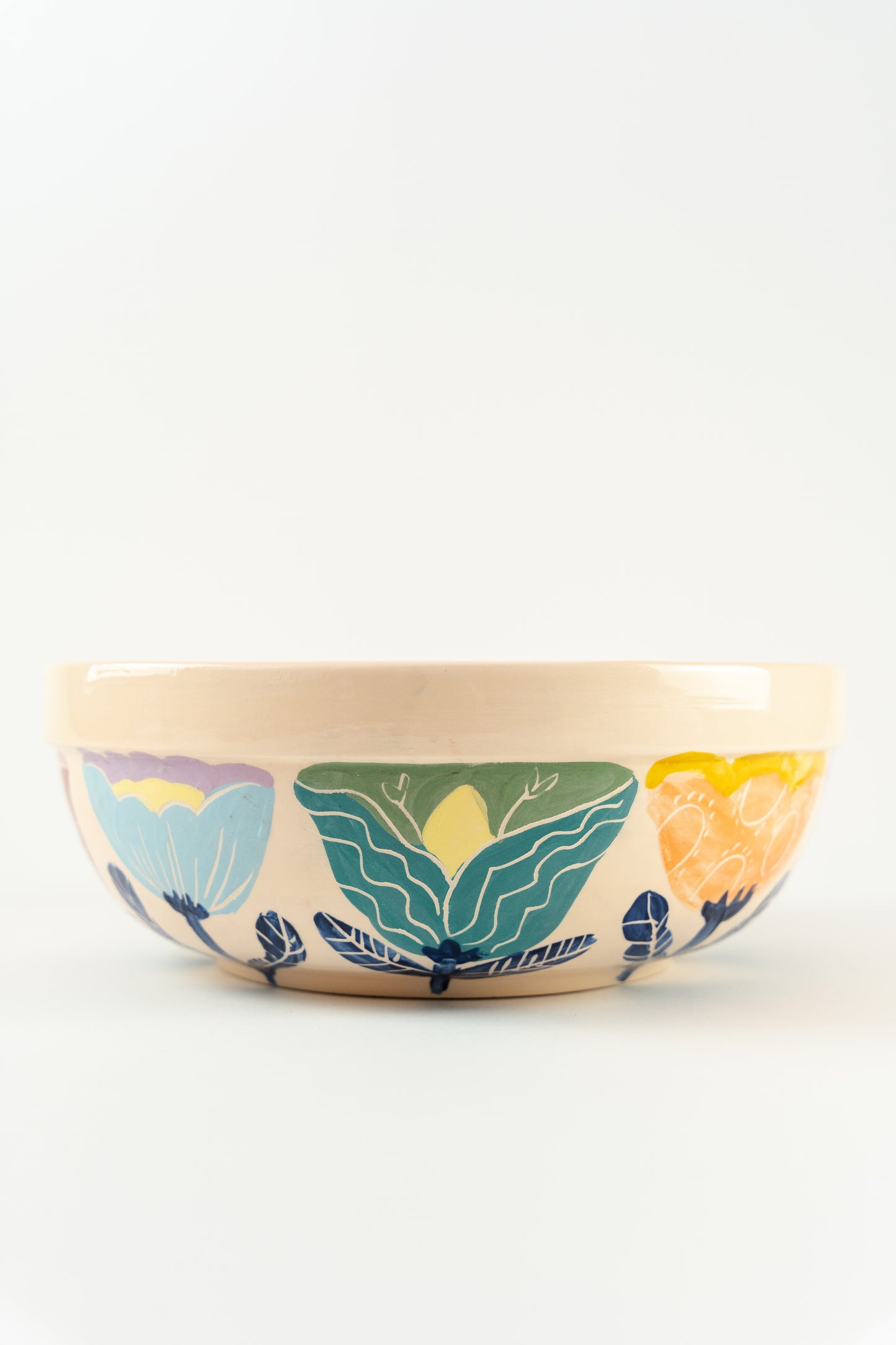 The side of the Handmade ceramic serving bowls fpor salads, with colorful flower details and a kind face design on the bottom of the bowl