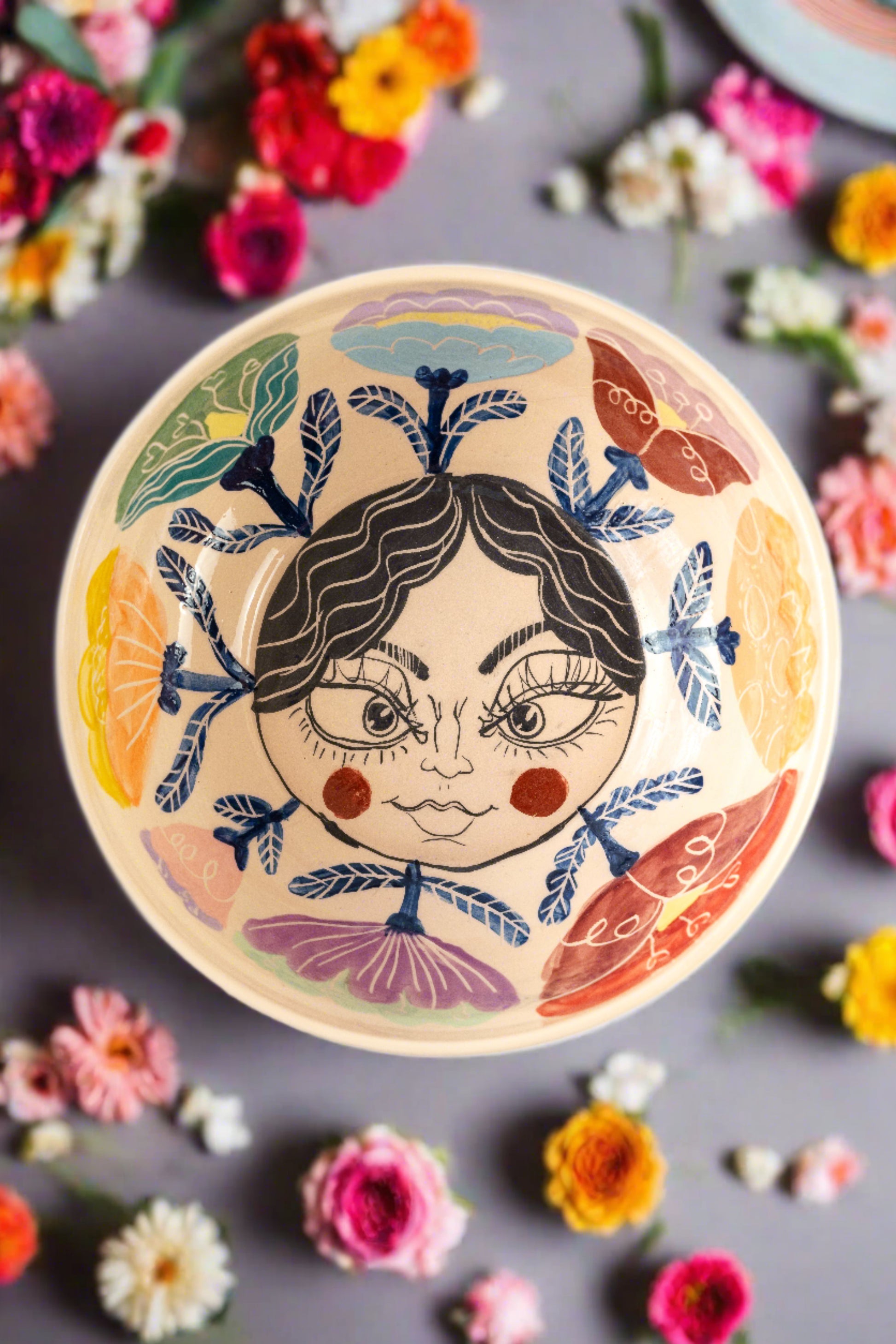 Handmade ceramic serving bowls fpor salads, with colorful flower details and a kind face design on the bottom of the bowl
